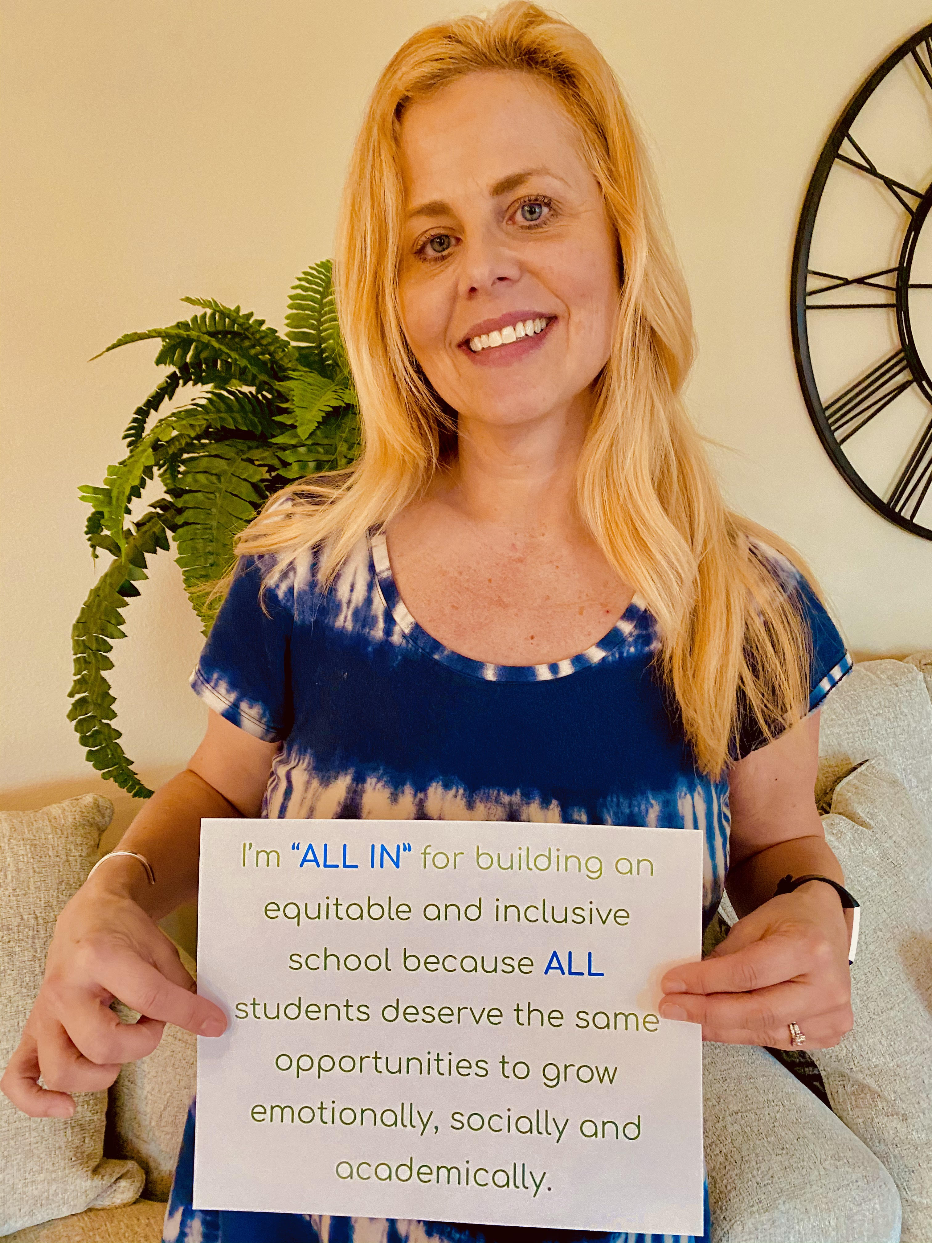 Gwen Torsen holding a sign "I'm all in for building an equitable and inclusive school because ALL students deserve teh same opportunities to grow emotionally, socially and academically." 
