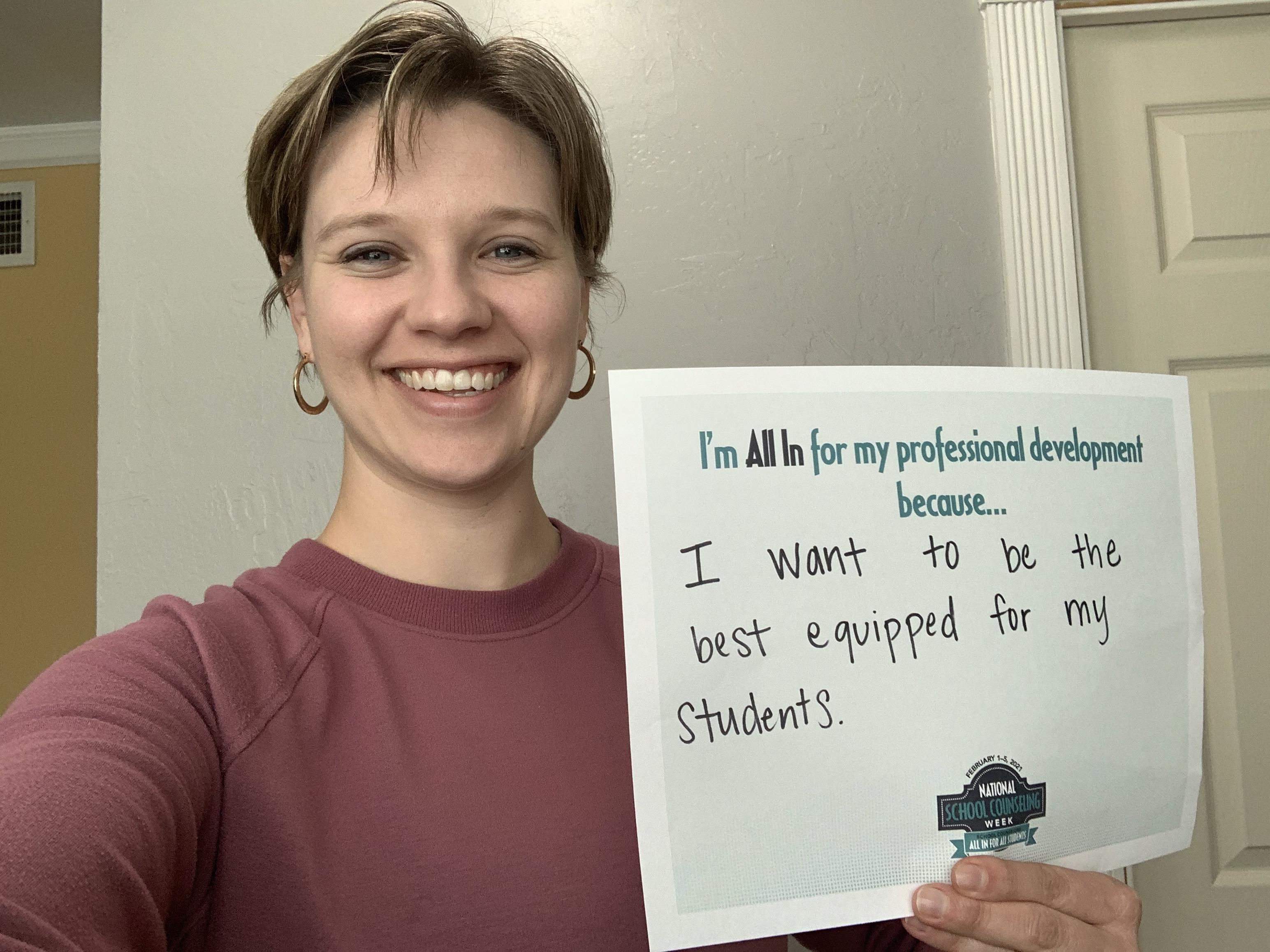 Kacie Salamanca with a sign "I'm all in for professional development because I want to be the best equipped for my students.