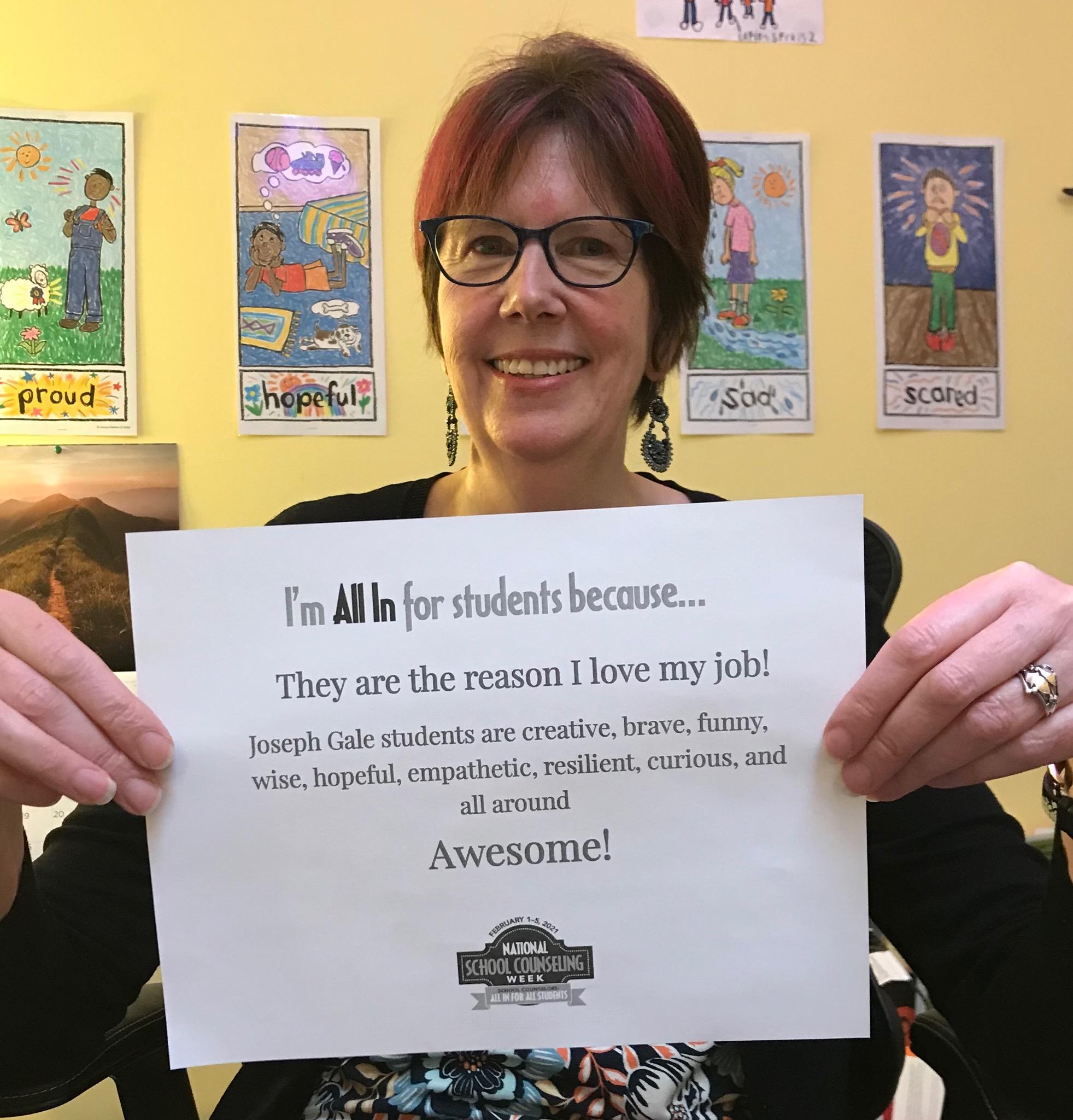 Nora Saunderson with a sign "I'm all in fo rstudents because they are the reason I love my job! Joseph Gale students are creative, brave, gunny, wise, hopeful, empathetic, resilient, curious and all around awesome. 